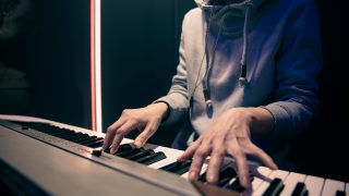 Female hands play the piano. Concept of music recording, rehearsal or live performance.